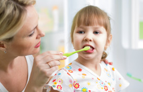 mother teaches kid teeth brushing